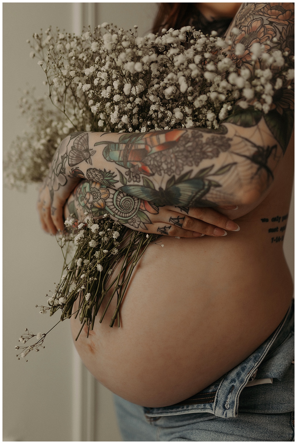 woman tightly holds a bouquet of flowers over her pregnant belly for Minneapolis Boudoir Photographer