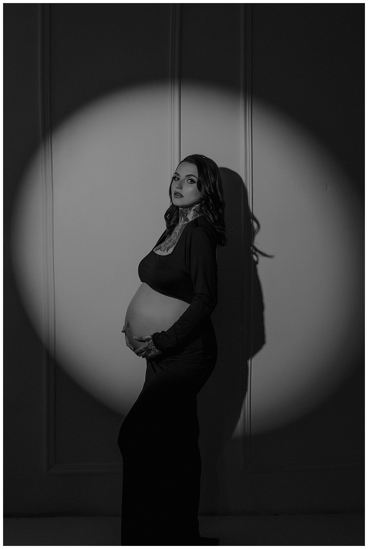 Woman holds her baby bump during heer Maternity Boudoir Session