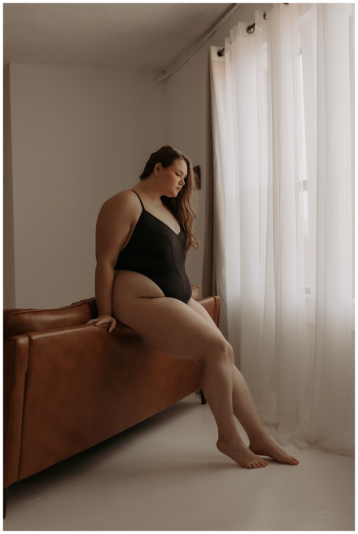 Adult wears black lingerie leaning against the couch showing Why Trust And Connection With Your Boudoir Photographer Are Important 