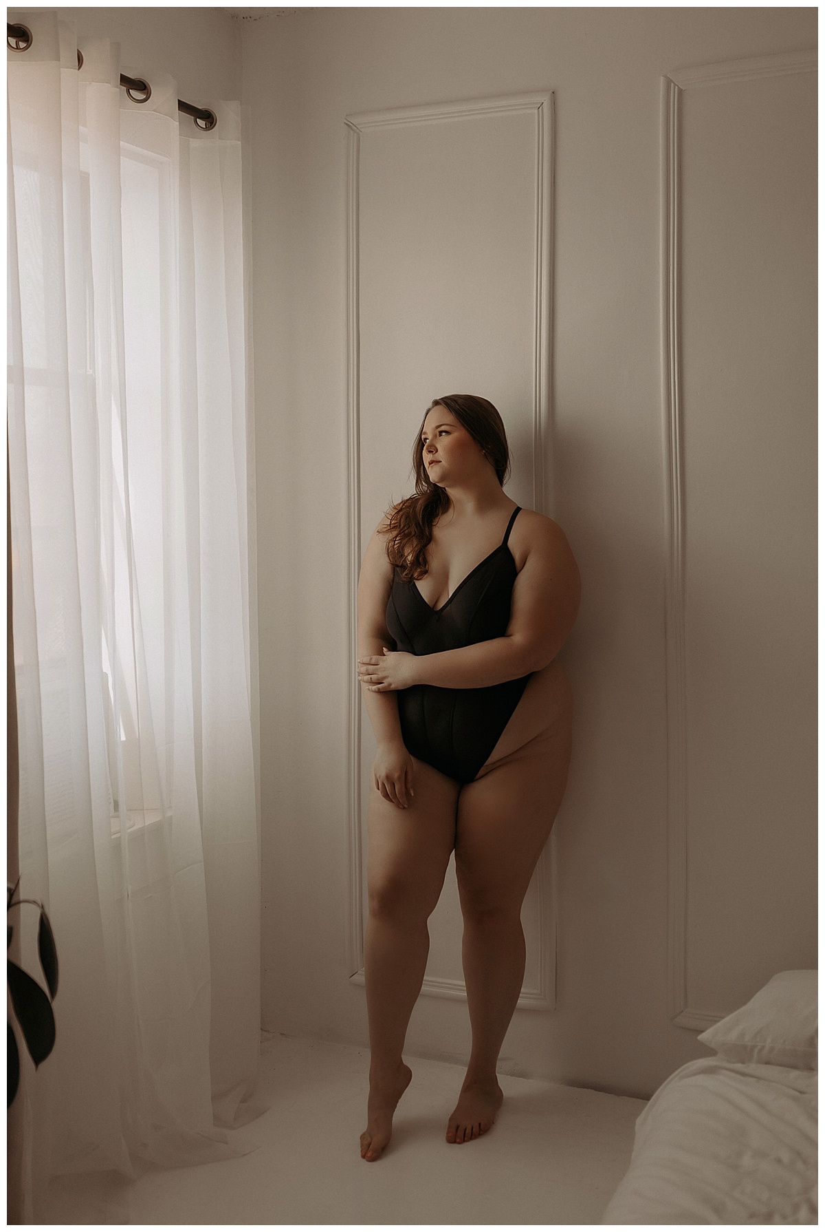 Adult leans against the wall wearing black lingerie for Mary Castillo Photography