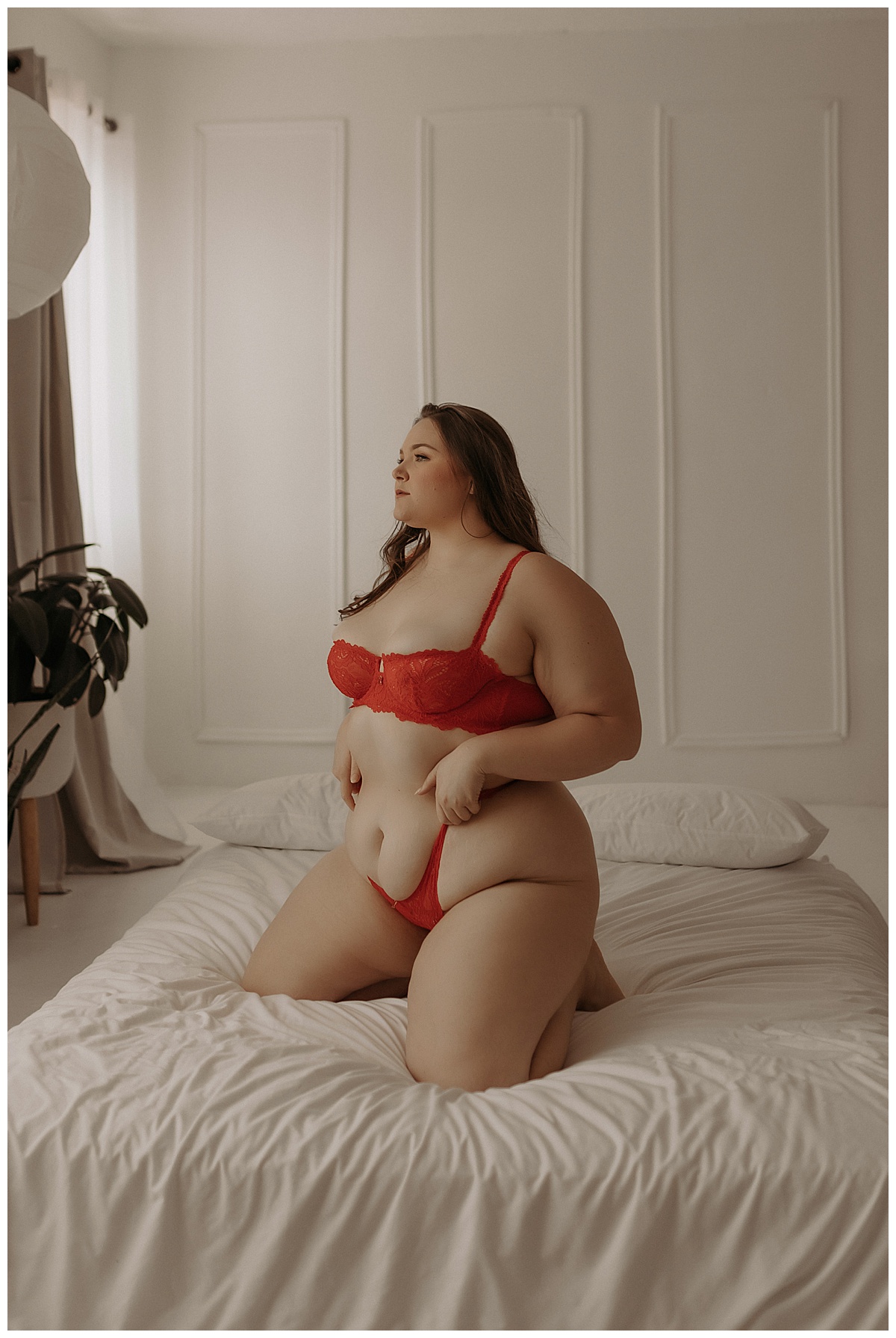 Person kneels on the bed wearing red lingerie for Minneapolis Boudoir Photographer