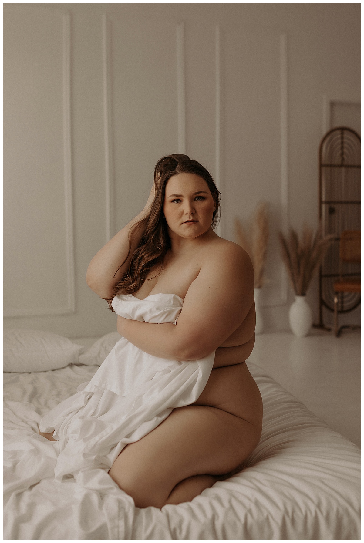 Female wraps sheet around her body for Minneapolis Boudoir Photographer