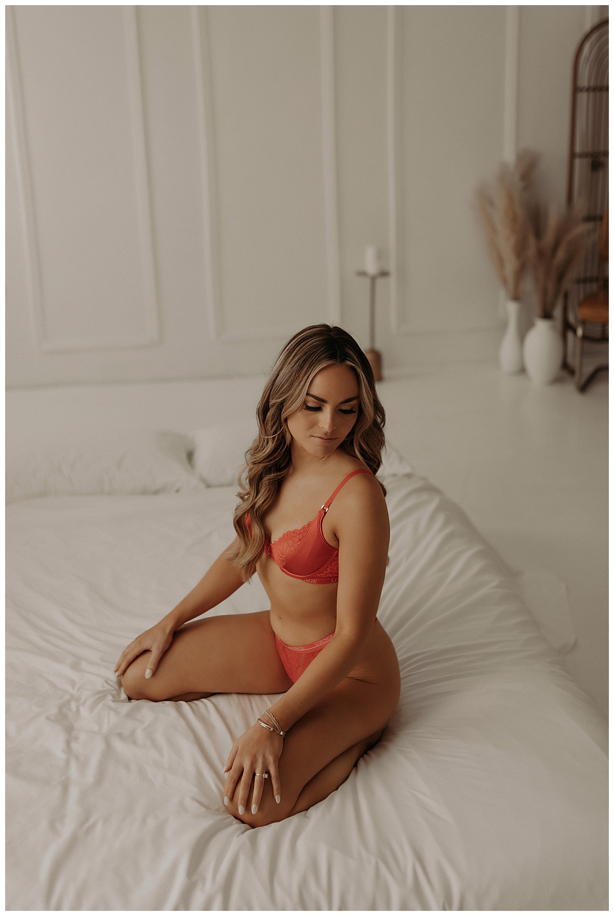 Woman kneels on bed wearing red lingerie for her Bridal Boudoir Session 