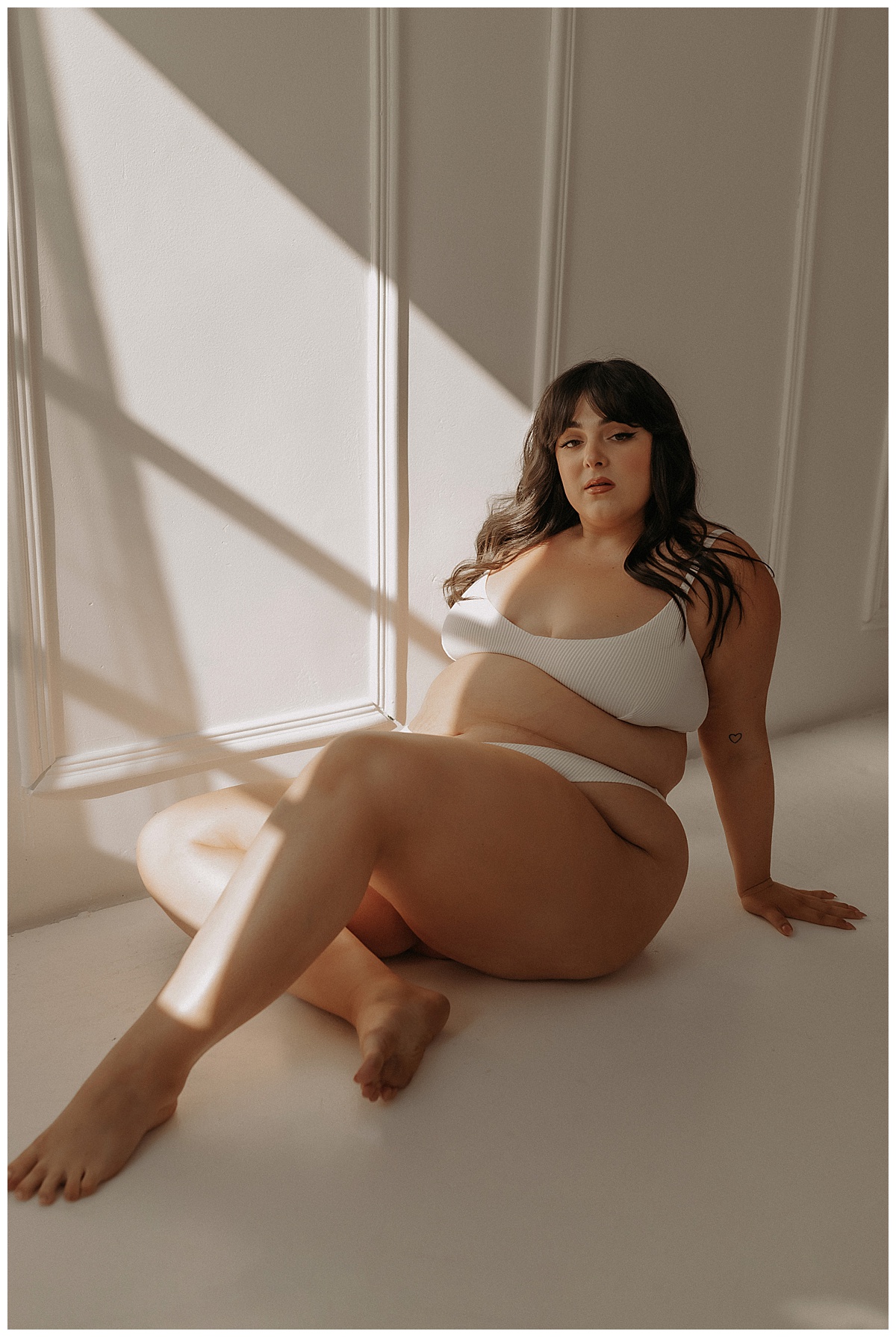Female sits on the floor wearing lingerie for Minneapolis Boudoir Photographer