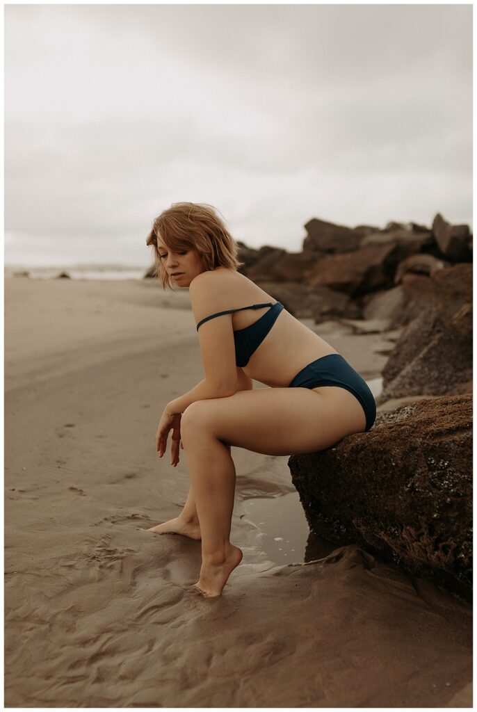 Adult leans forward while sitting on rocks for Mary Castillo Photography