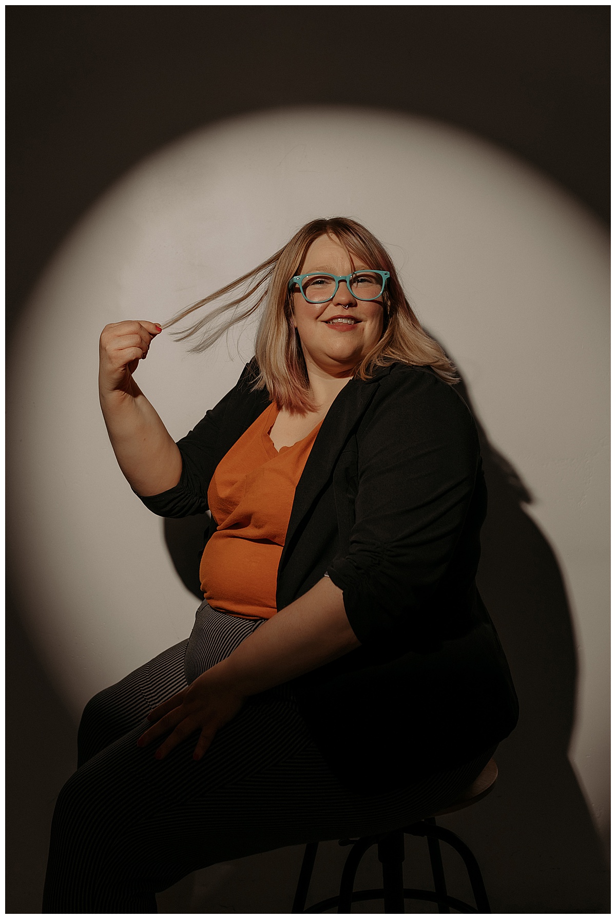 Woman wears bold and bright colors sitting on the stool following tips for Preparing for Your Creative Headshot Session