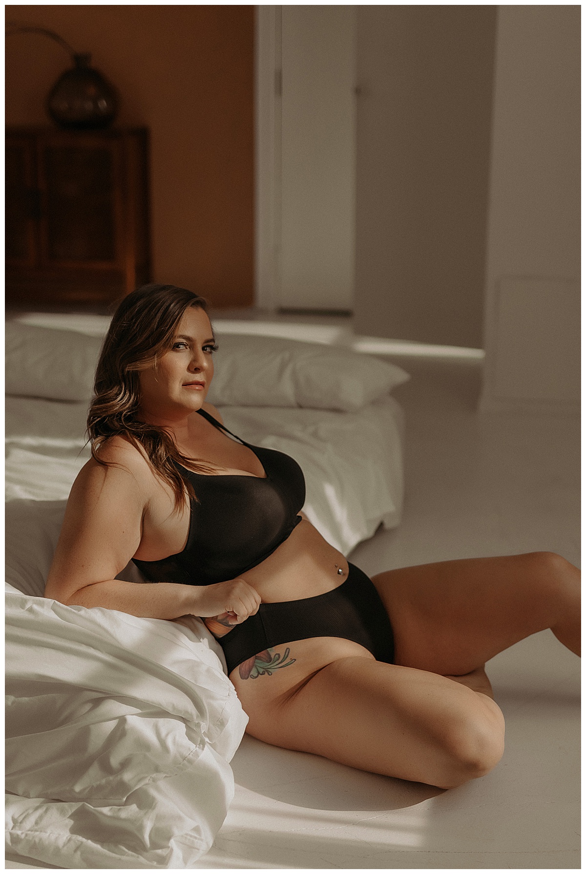 Person wears black lingerie while leaning against the bed for Minneapolis Boudoir Photographer