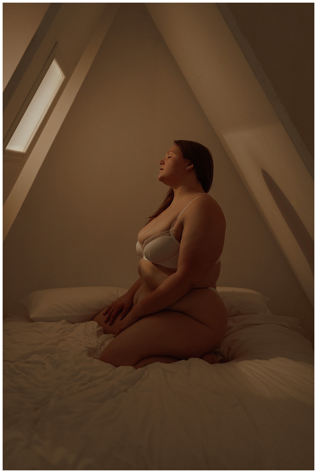 Woman kneels on the bed under an A-frame light for Mary Castillo Photography