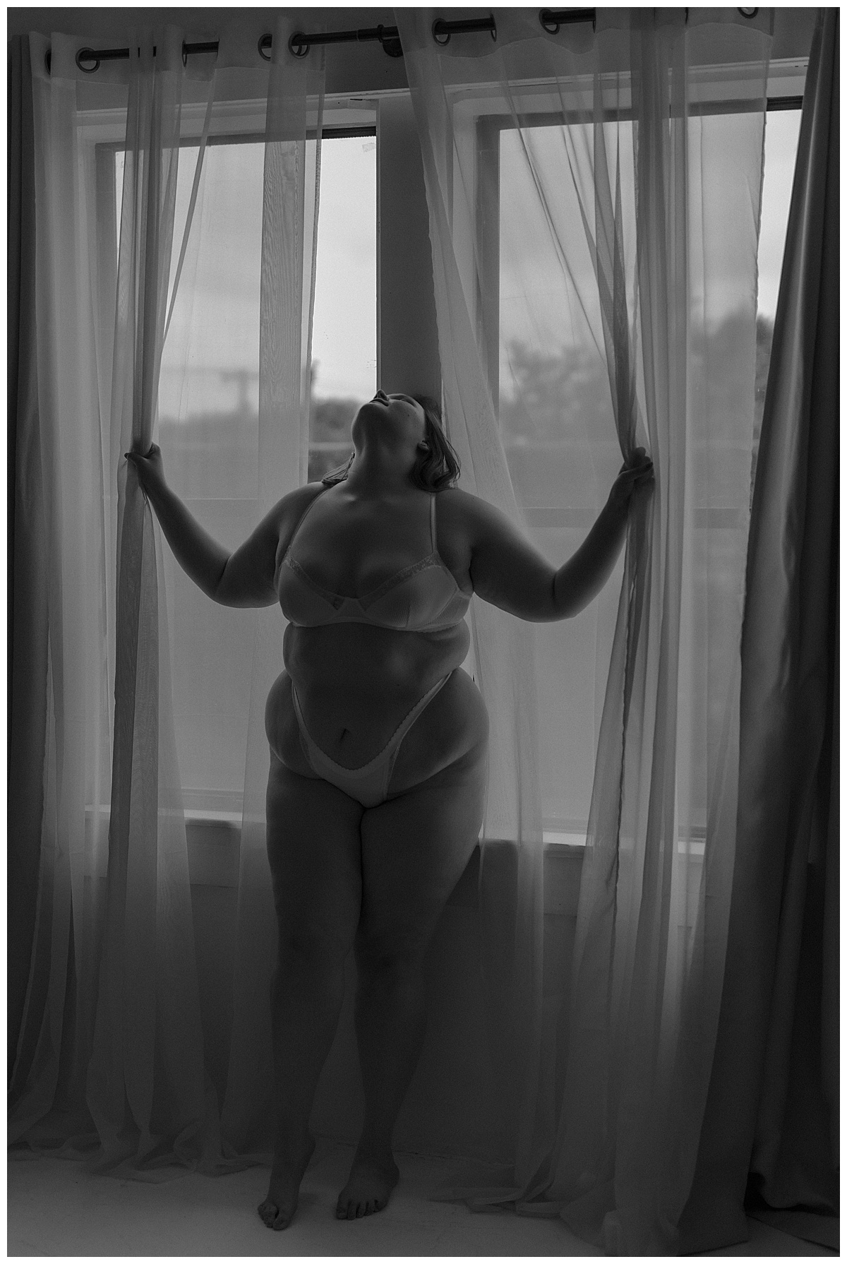 Woman tugs at window shades for Mary Castillo Photography