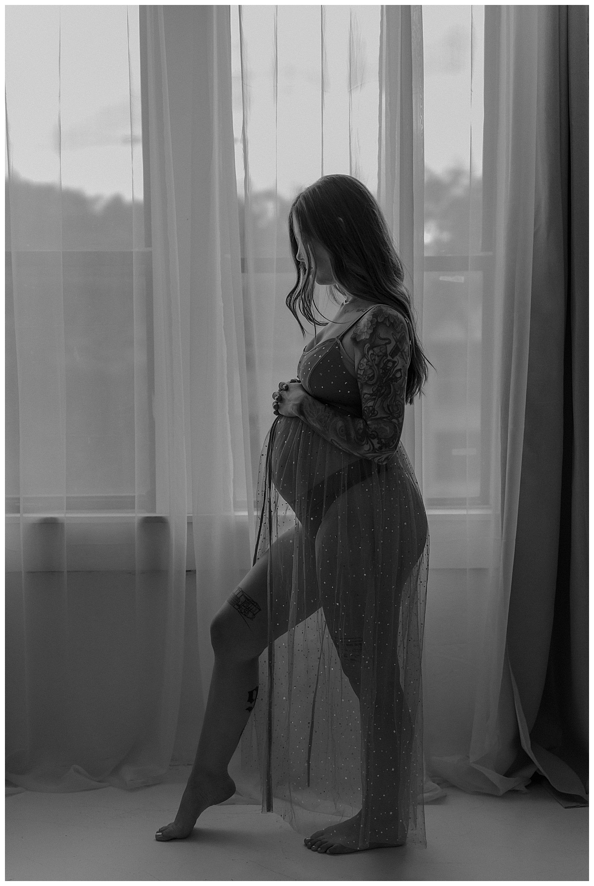 Adult stands in front of the window showing What to Wear for Your Maternity Boudoir Photos