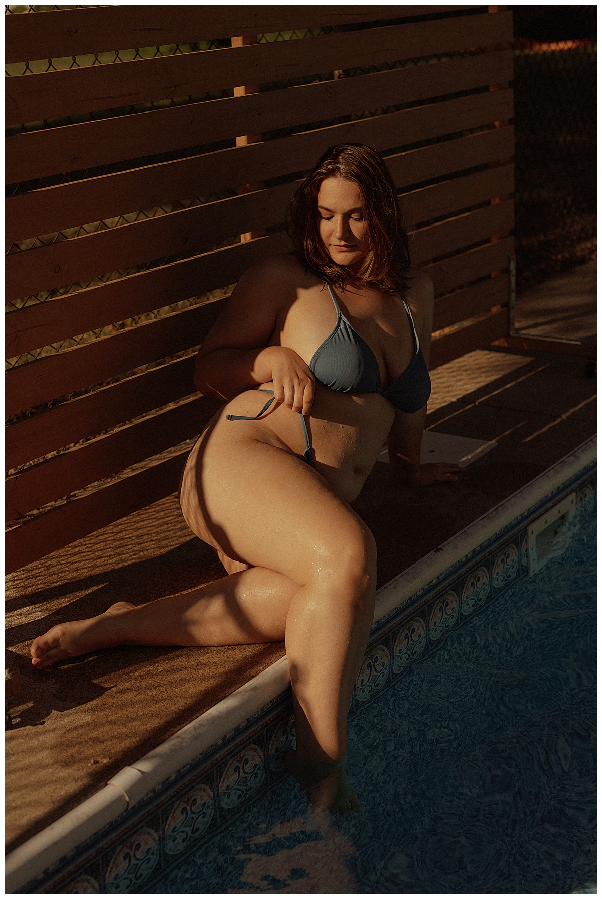 Woman lays outside the pool wearing a blue swimsuit for Minneapolis Boudoir Photographer