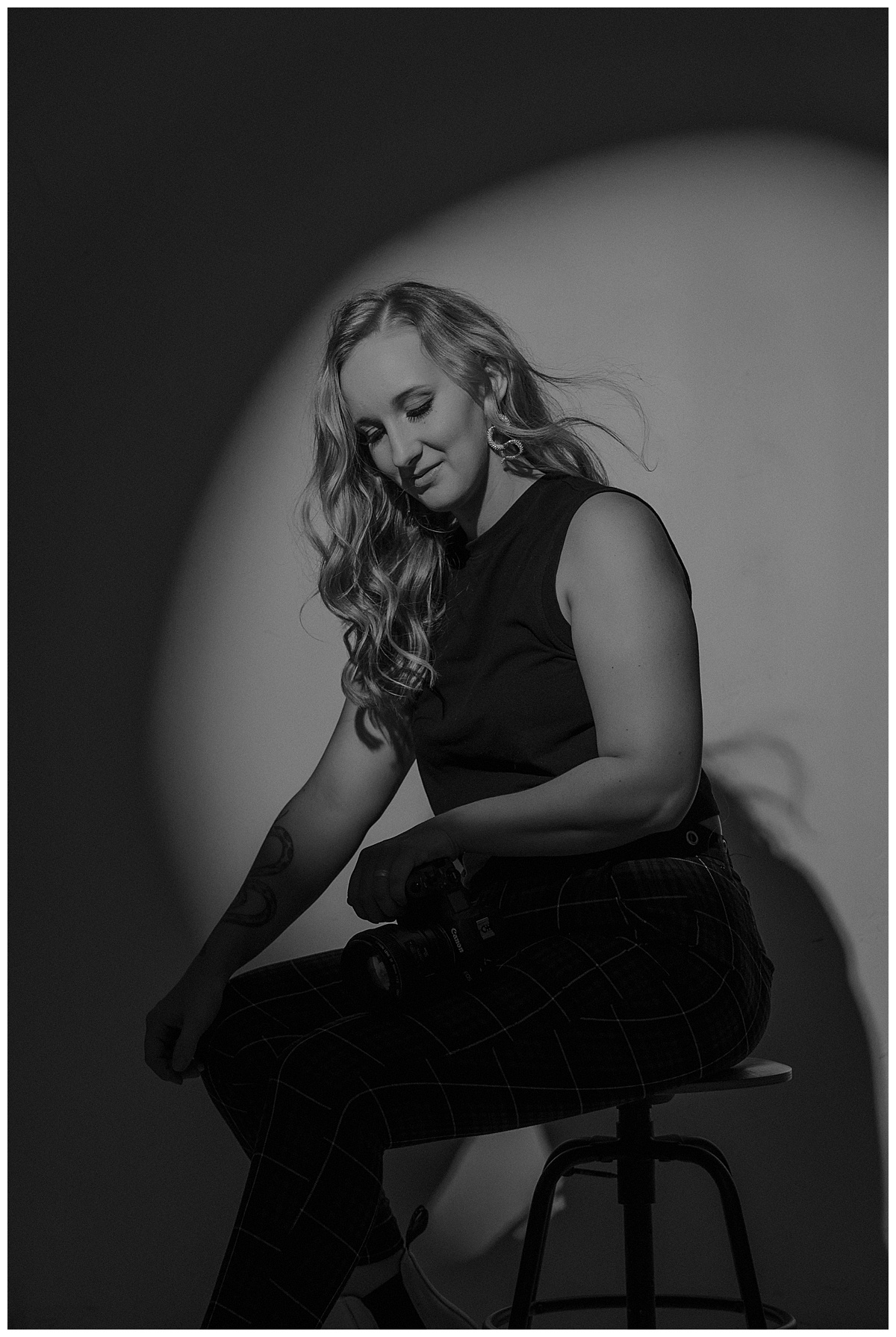 Adult sits on a chair while holding her camera for Mary Castillo Photography