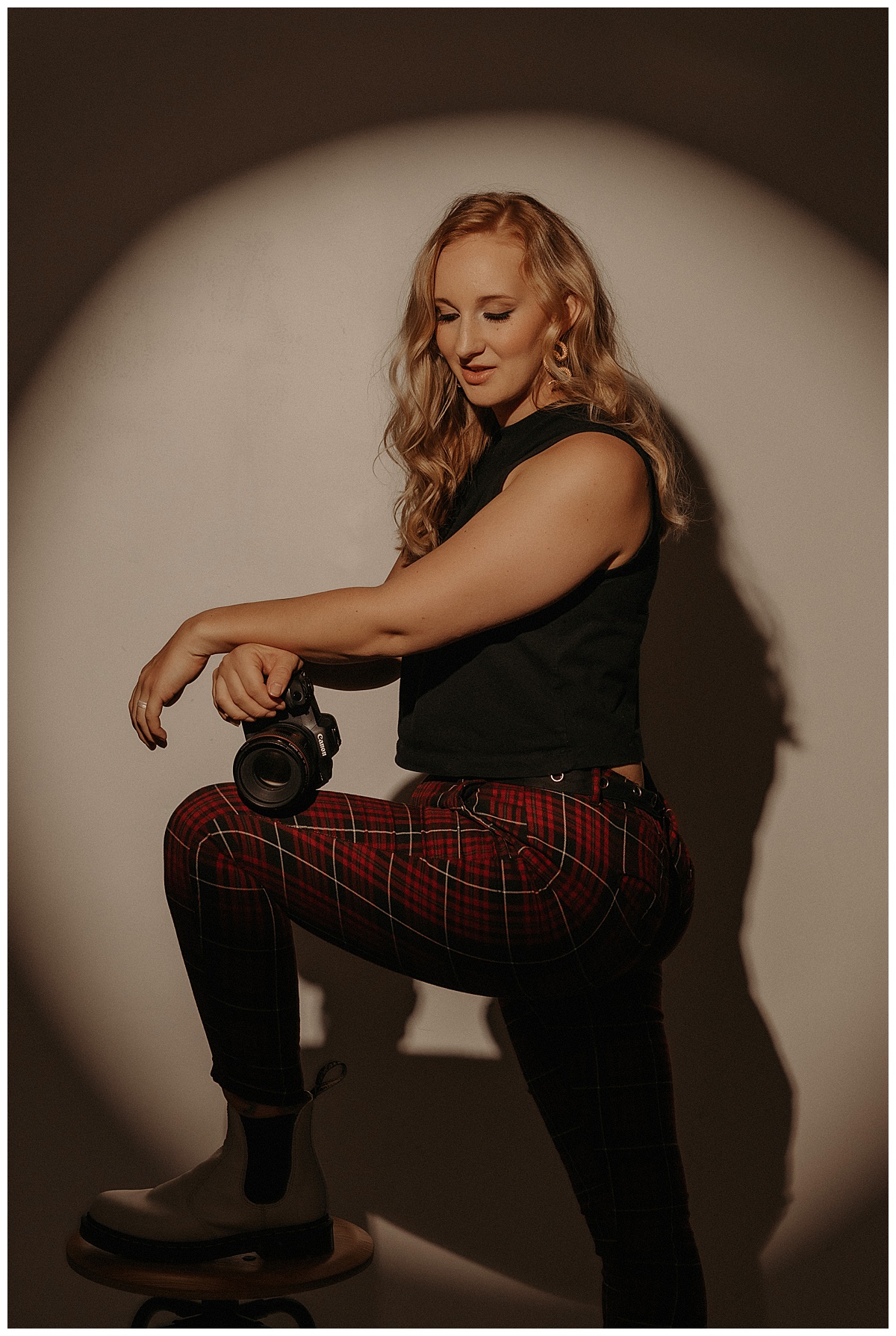 Woman kneels on a stool while holding her camera for Minneapolis Boudoir Photographer