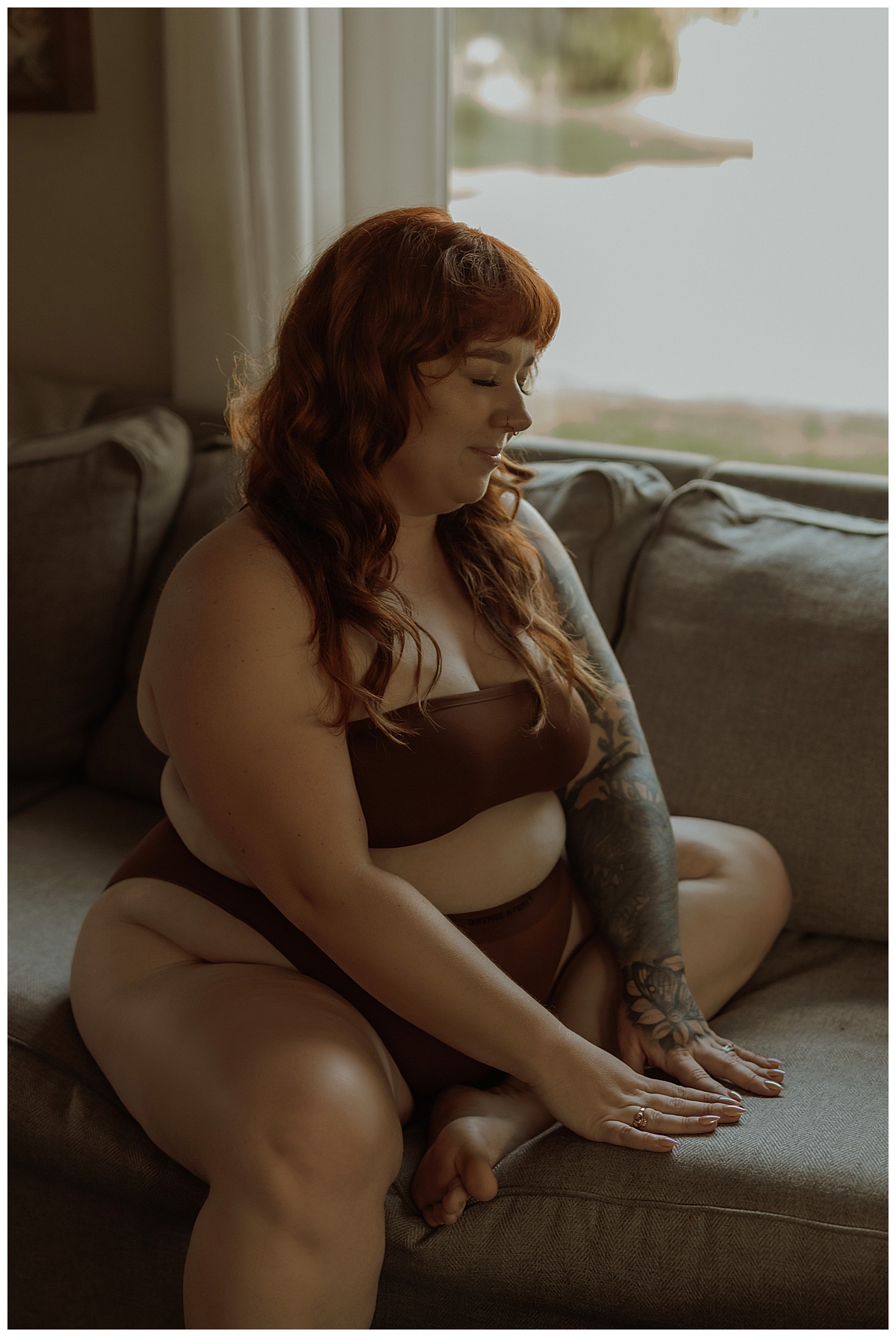 A female sits on the couch wearing brown lingerie during this Moody Vibes boudoir home session 