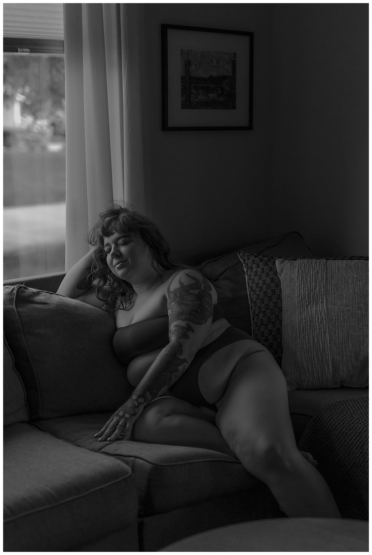 Female sits on a couch during her boudoir home session by Mary Castillo Photography