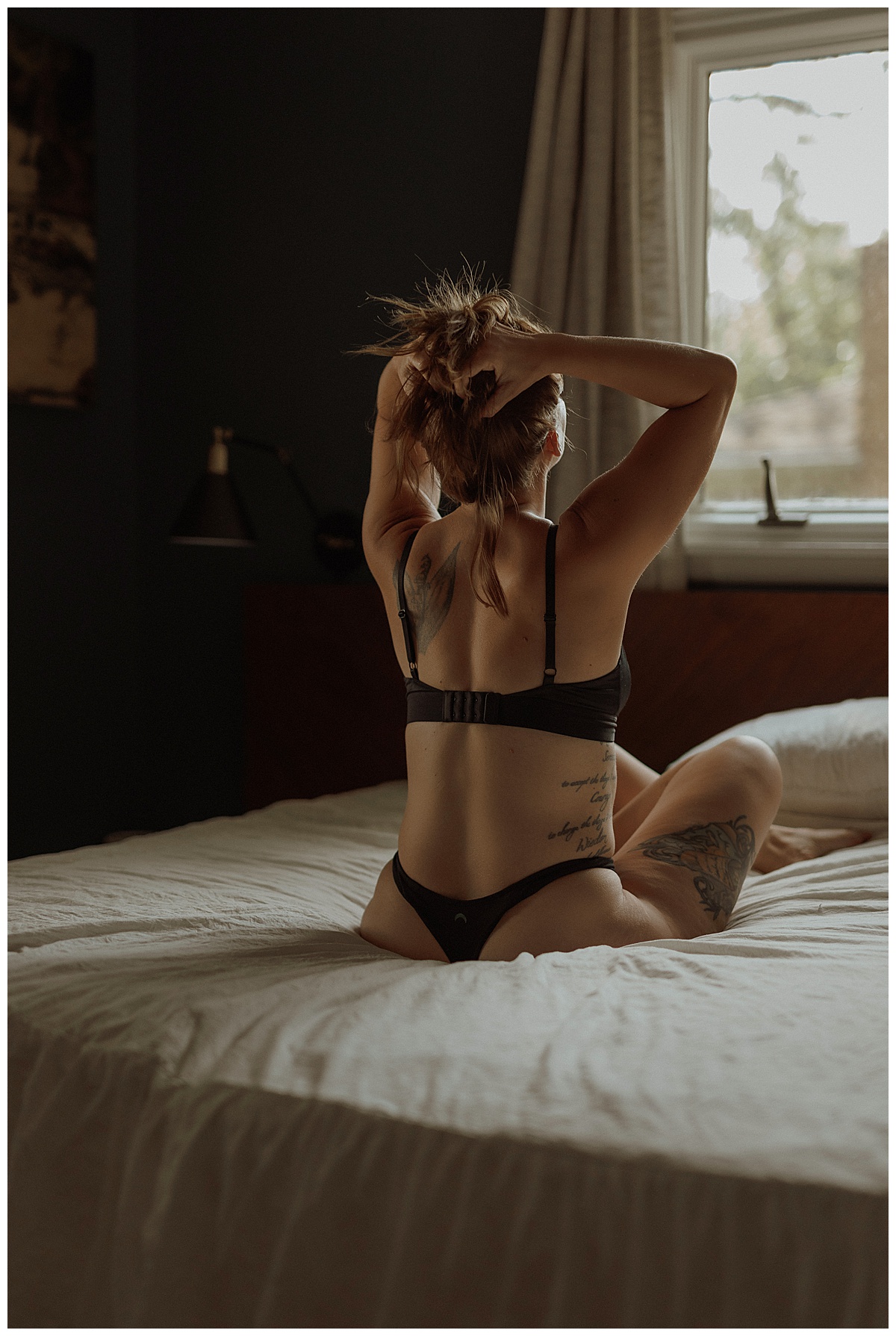 Female holds her hair up wearing black lingerie by Minneapolis Boudoir Photographer