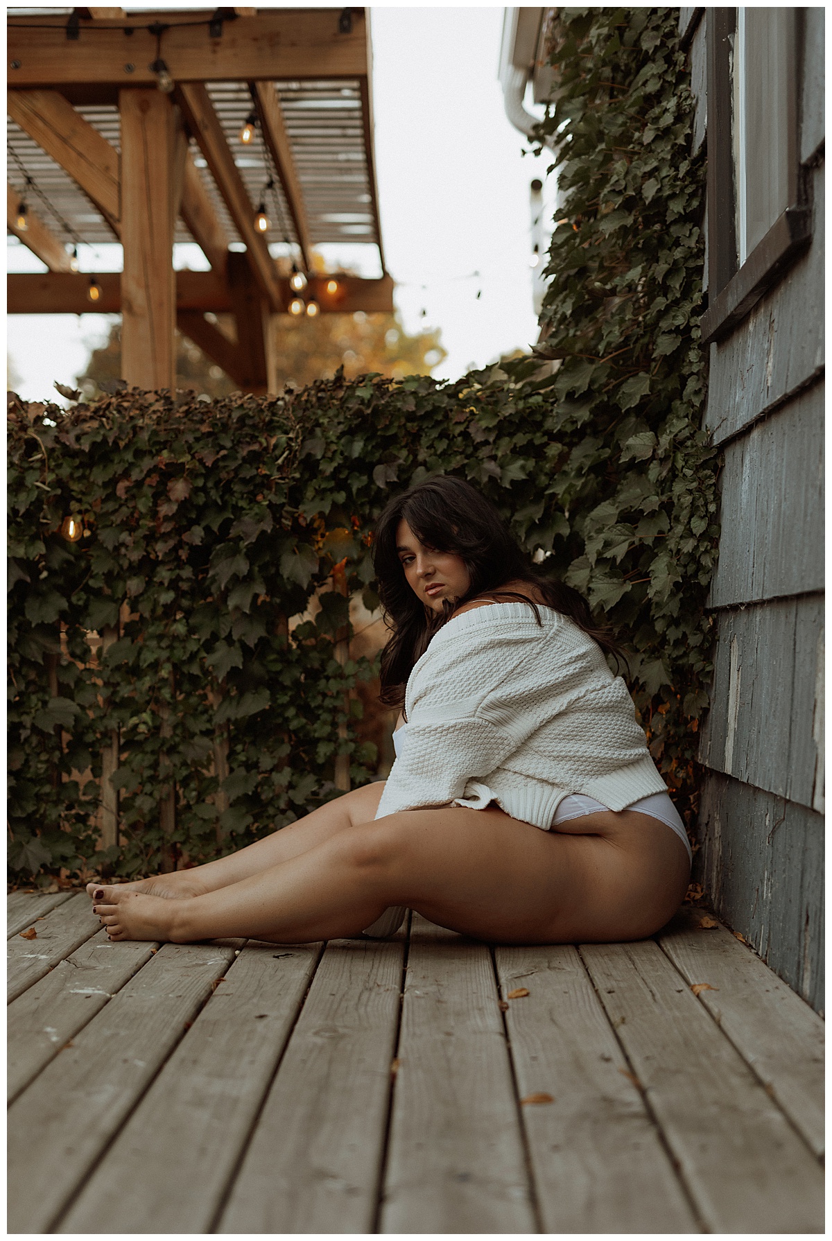 Adult sits on the floor while modeling for Black Friday Sales for boudoir photographer