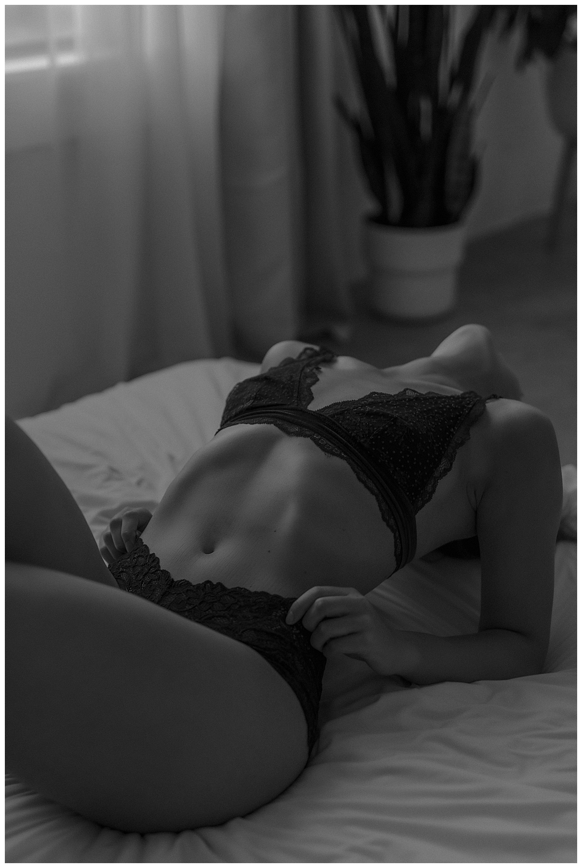 An adult lays on the bed wearing lingerie for Minneapolis Boudoir Photographer