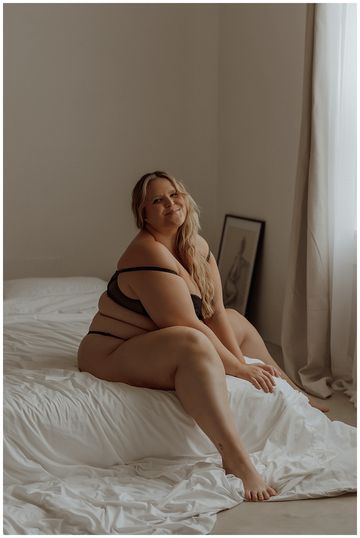 Person sits on the edge of the bed wearing a black lingerie set for Minneapolis Boudoir Photographer