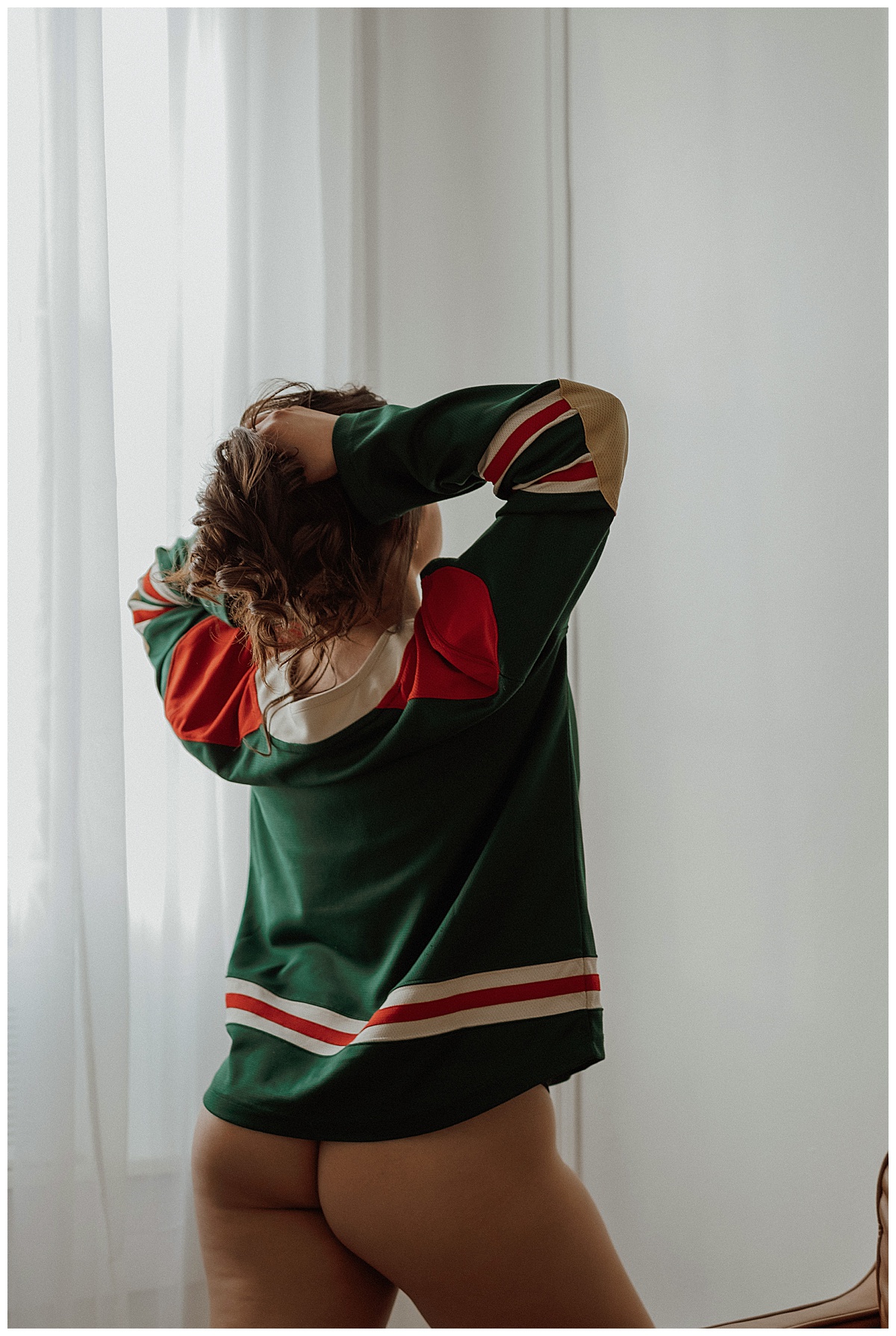 Woman runs her fingers through her hair during her Light and Airy  boudoir session