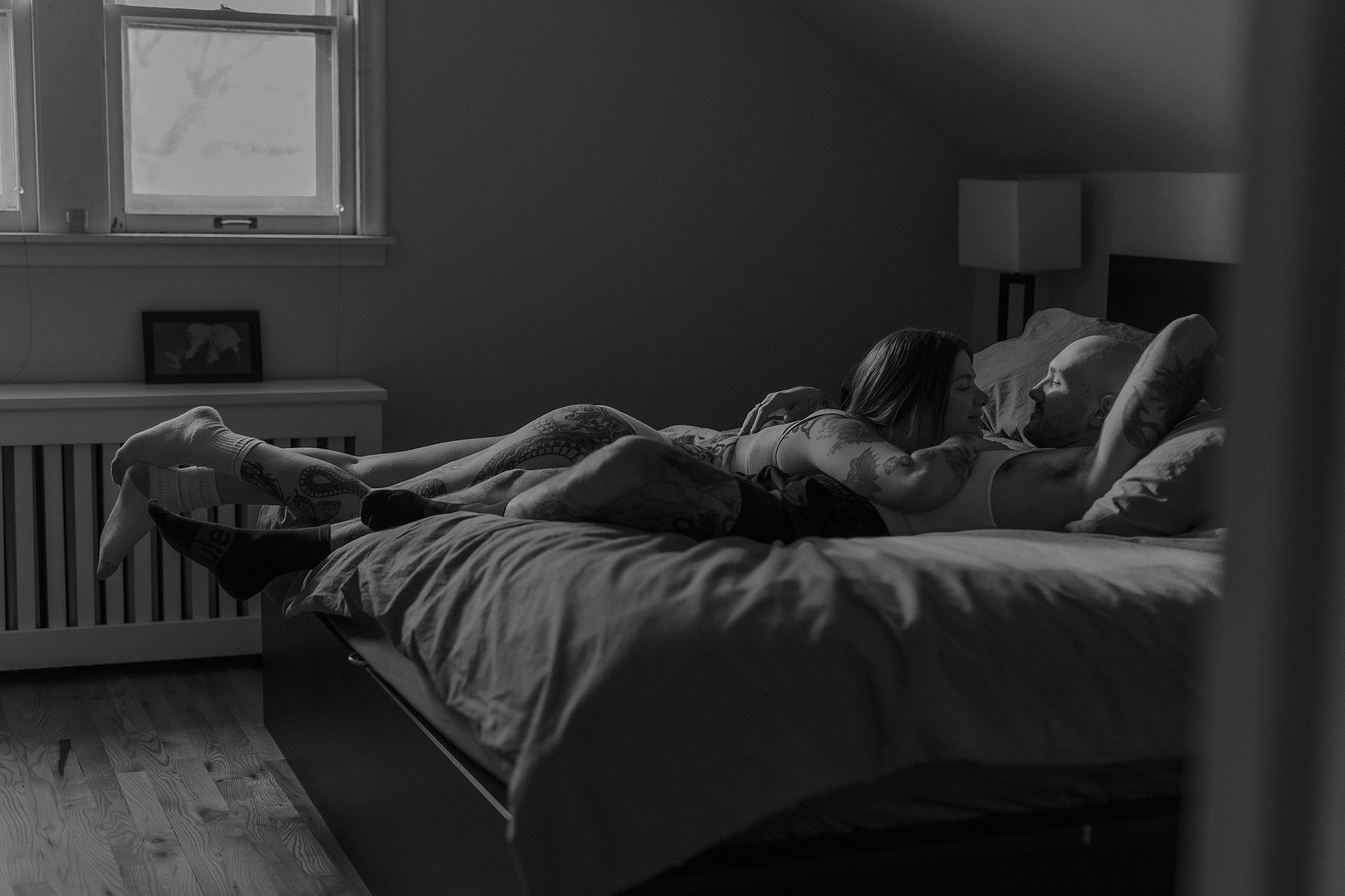 Black and white photo of couple cuddling on bed by Mary Castillo Photography