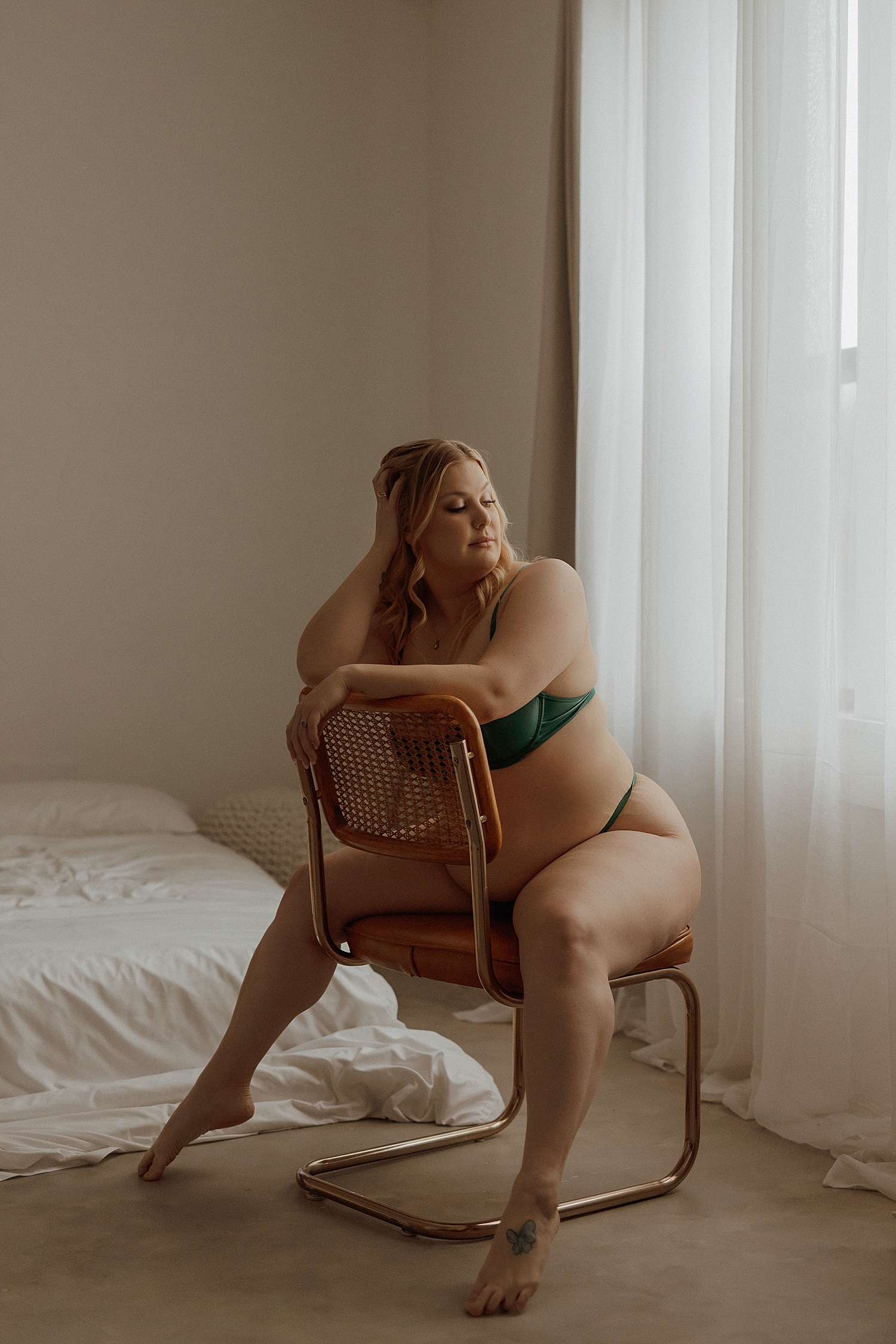 curvy woman sits in chair by window by Mary Castillo Photography