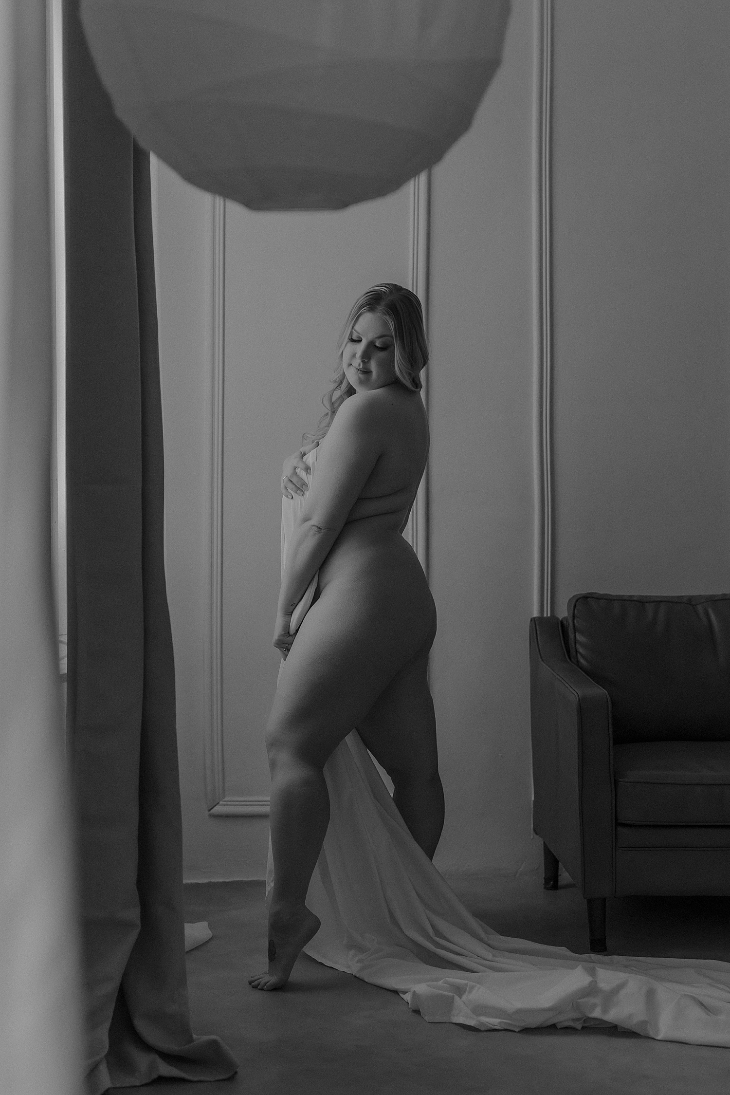 woman stands nude by the window by Minneapolis boudoir photographer 