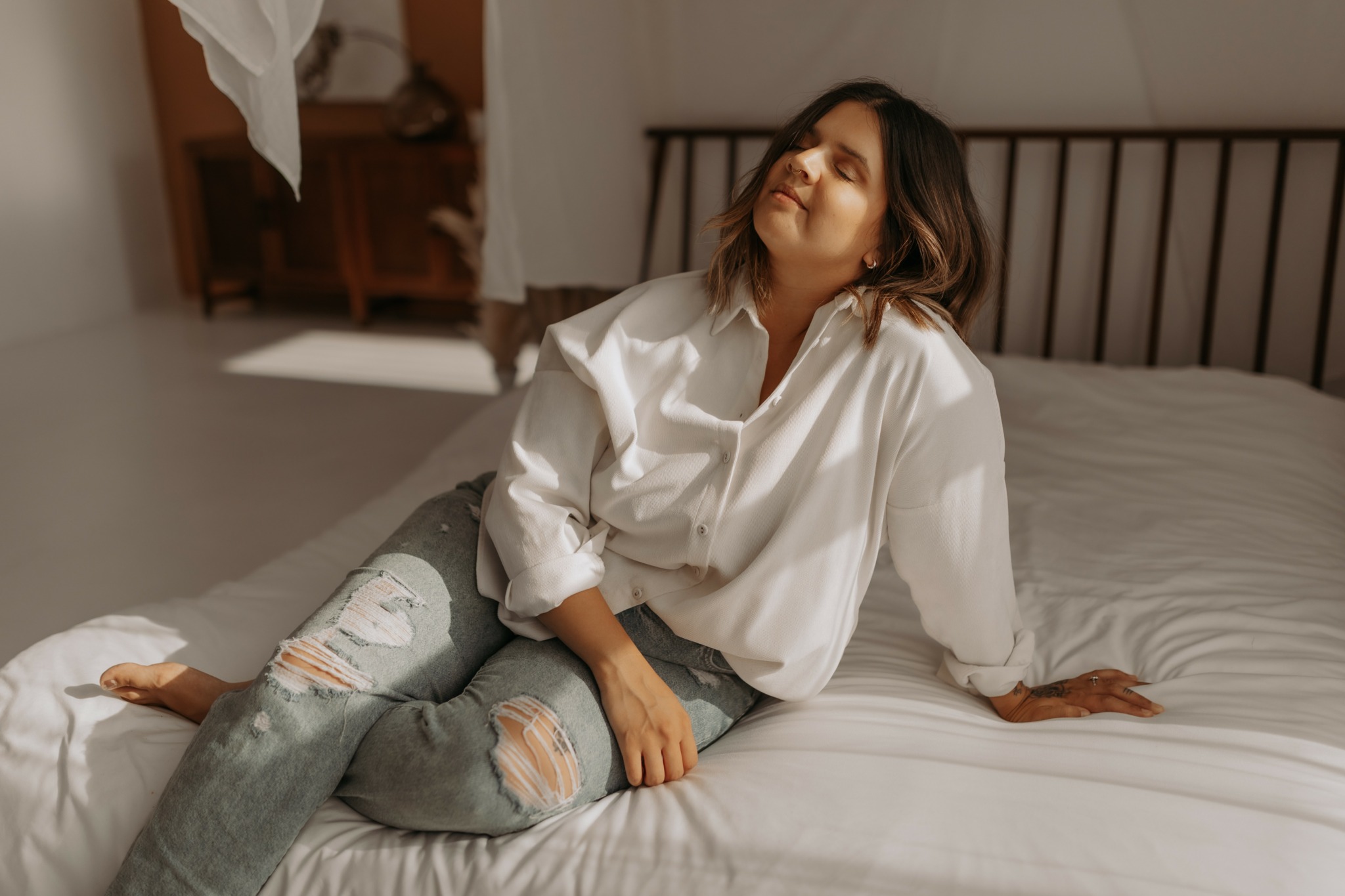 minneapolis boudoir photographer sits on bed in her studio 