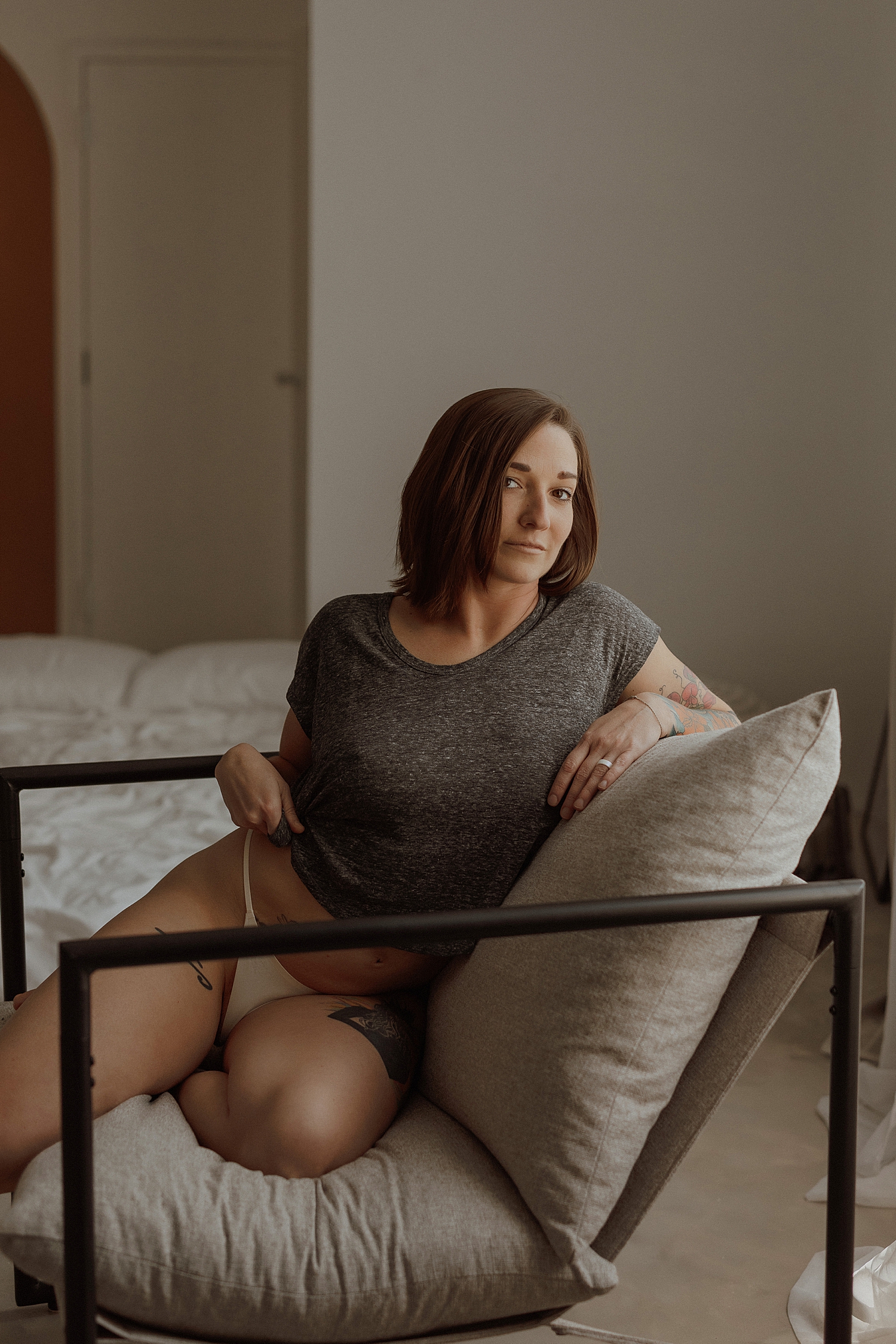 brunette in gray shirt sits in chair by Minneapolis boudoir photographer