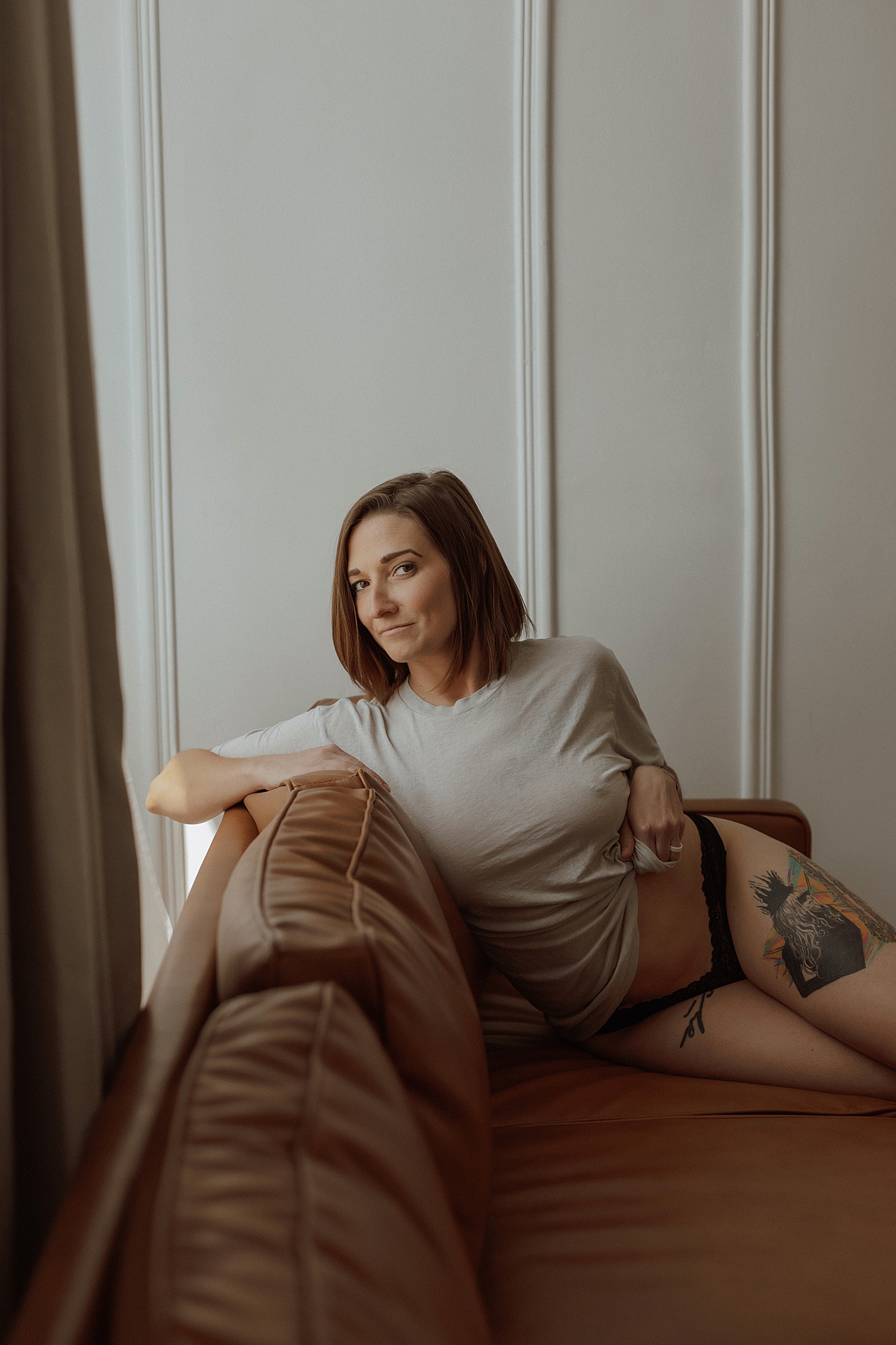 woman with tattoos leans on couch by Mary Castillo Photography