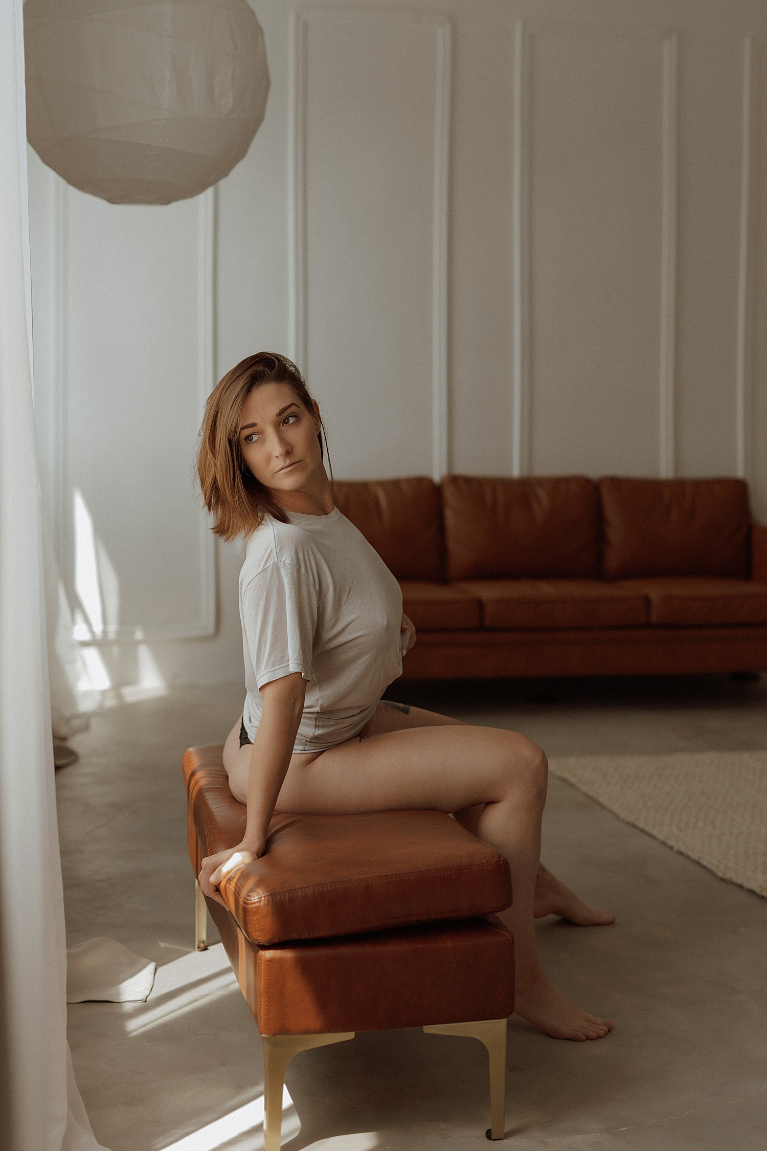 woman with short hair leans on leather bench by Minneapolis boudoir photographer