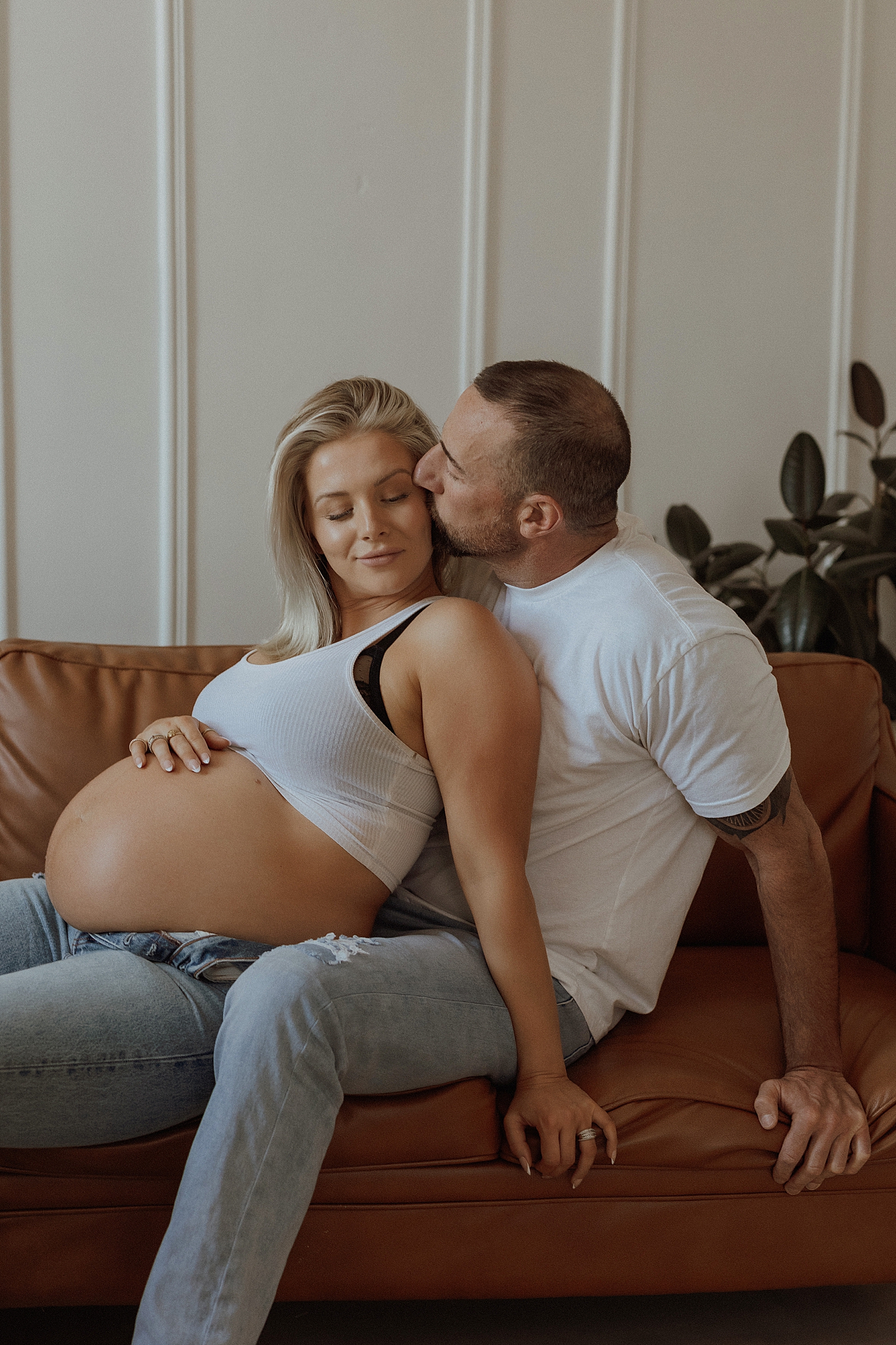 man kisses pregnant mama on couch by Minneapolis boudoir photographer