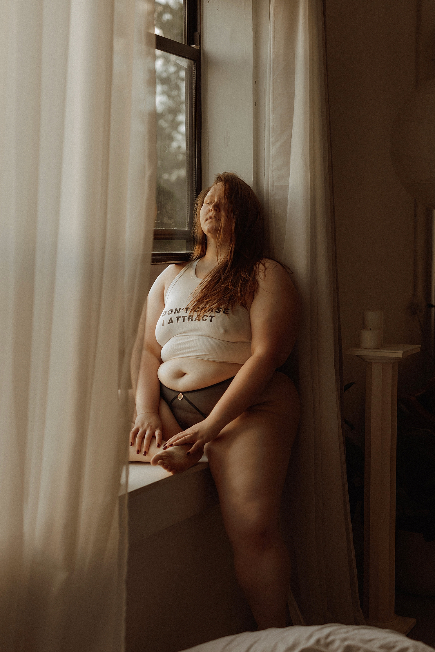 brunette straddles a window in evening light by Mary Castillo Photography