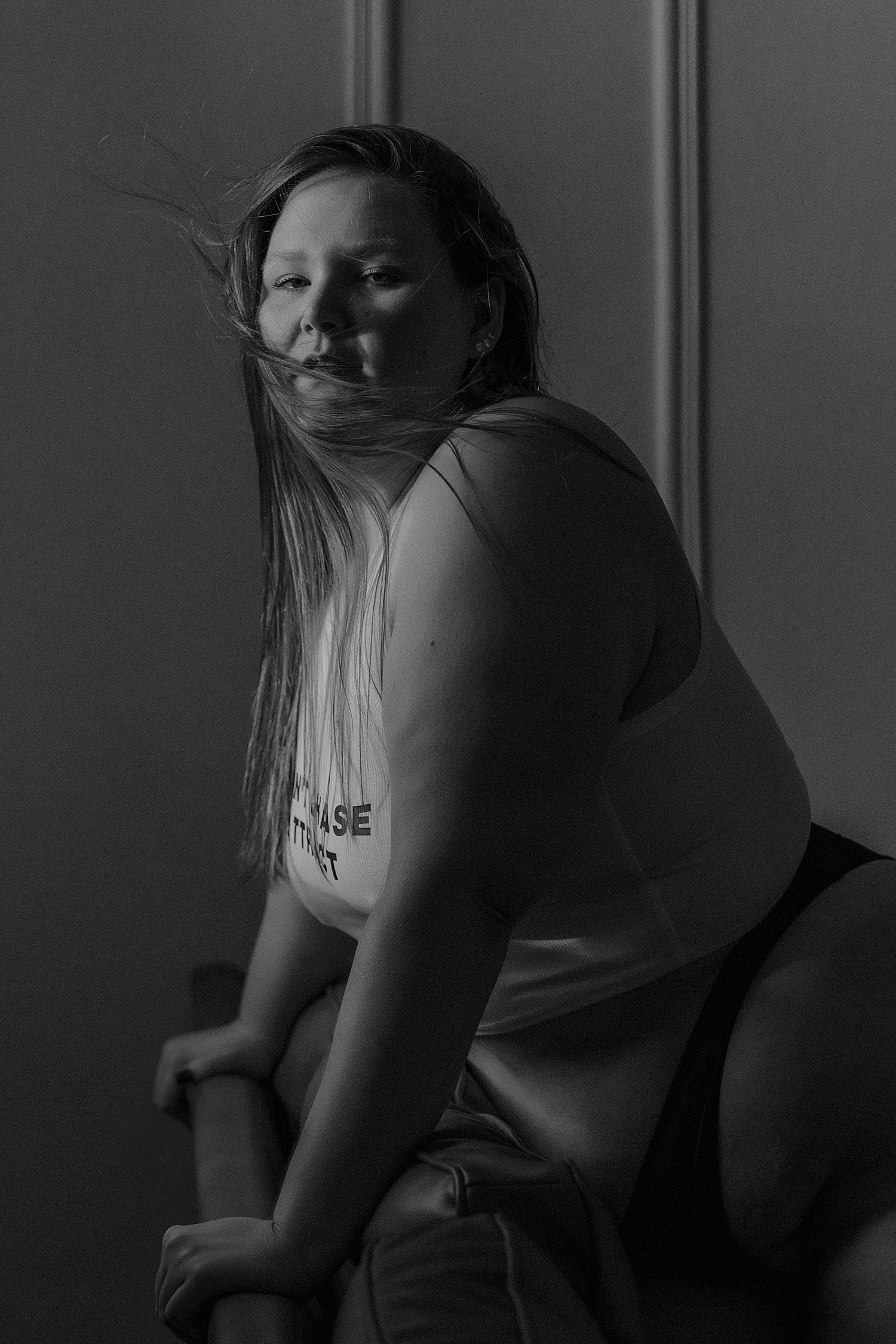 model in tank leans over the back of a couch for creative poses