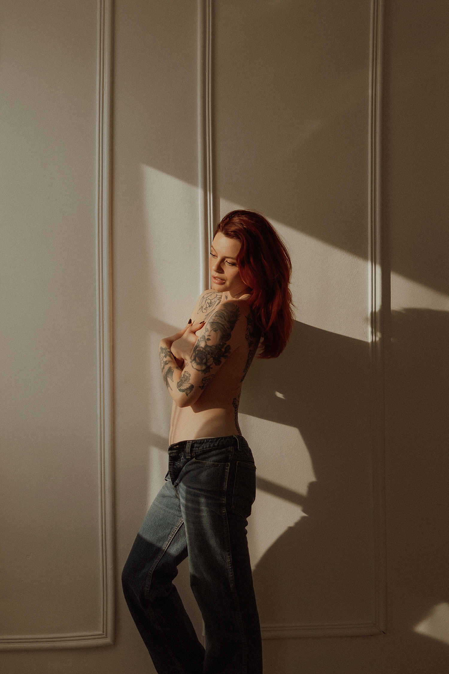 person wearing jeans stands in front of big windows by Minneapolis boudoir photographer