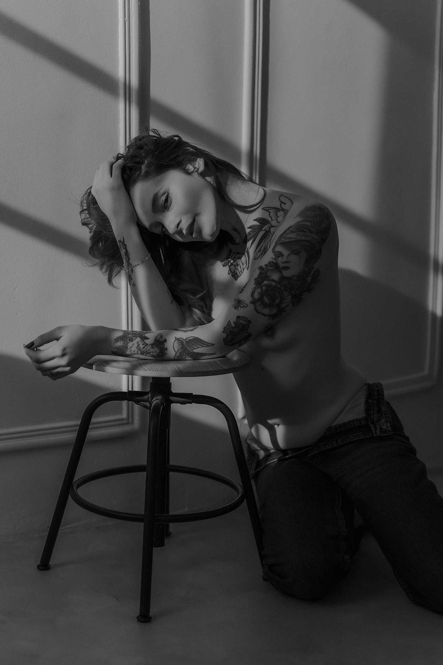 woman leans over stool in studio during evening by Minneapolis boudoir photographer