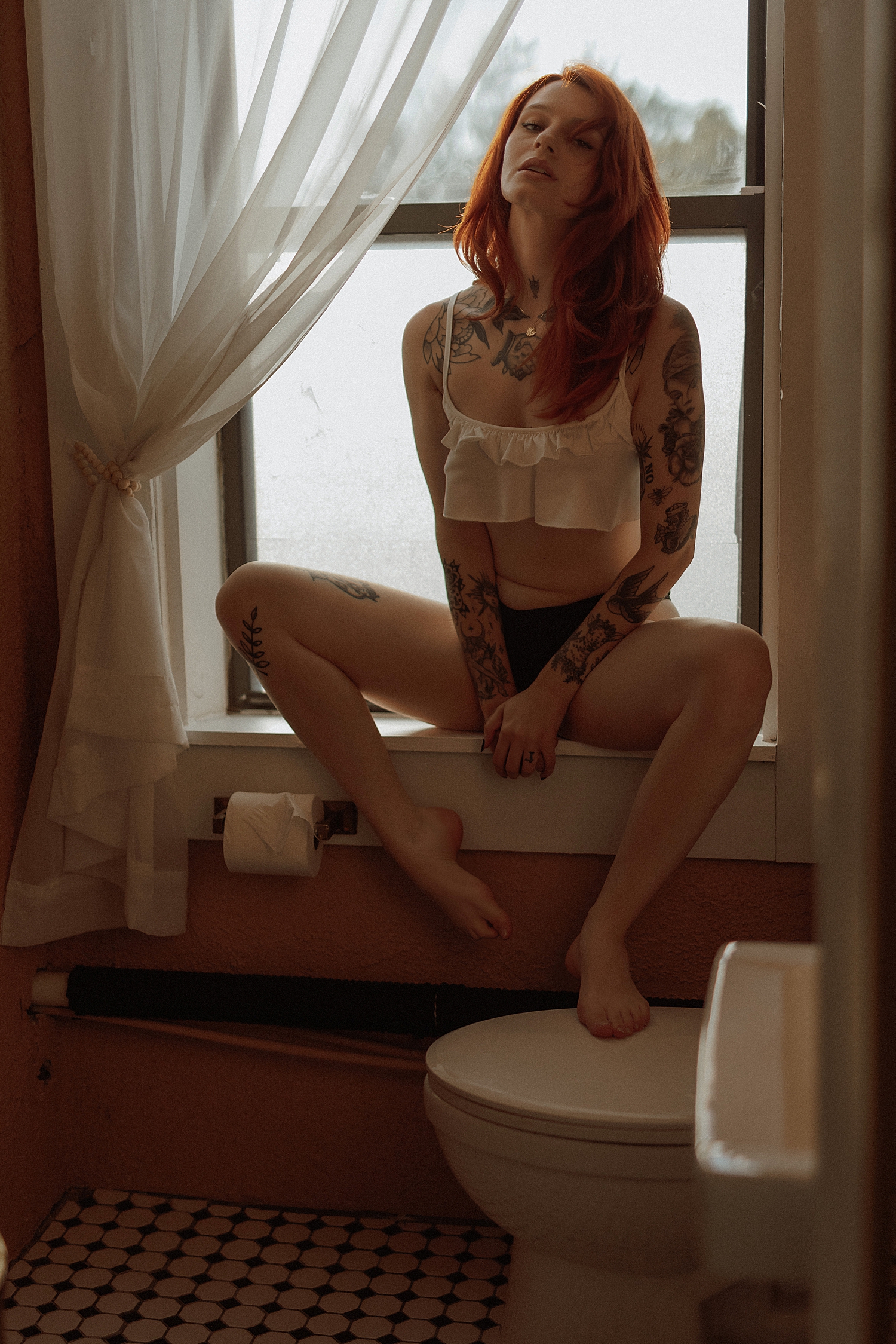 woman sits in window next to bathroom by Minneapolis boudoir photographer