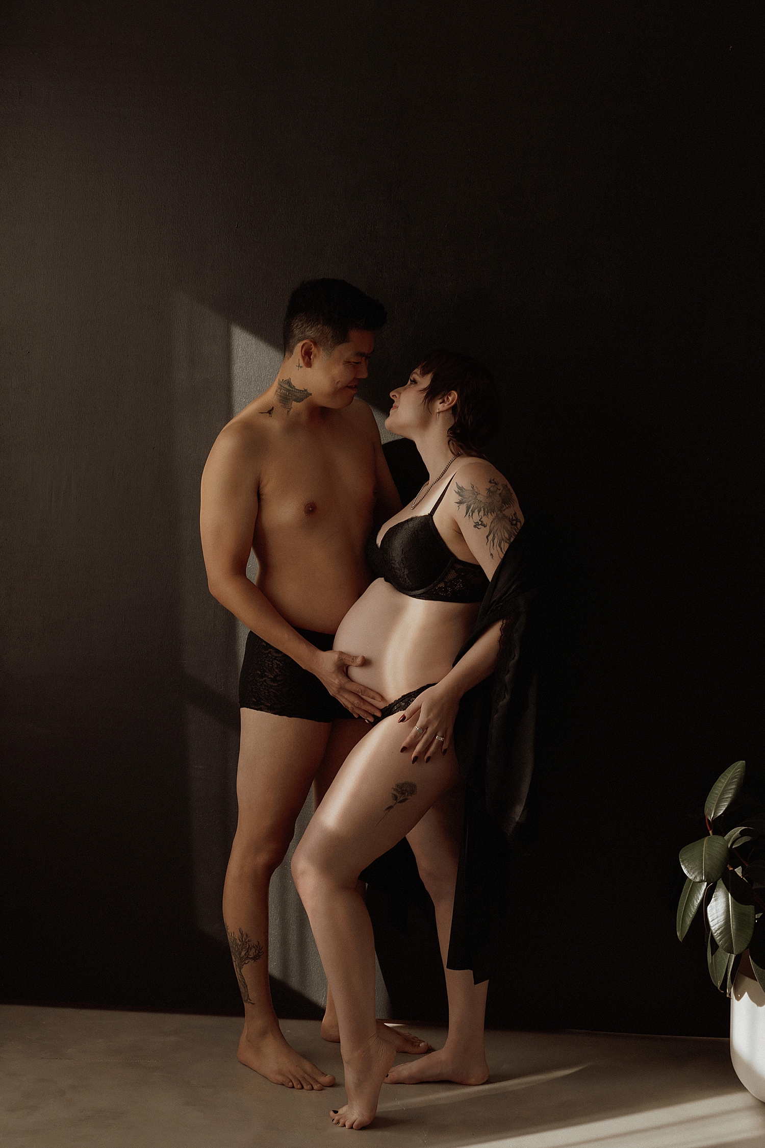 married couple embrace in front of black wall by Mary Castillo Photography